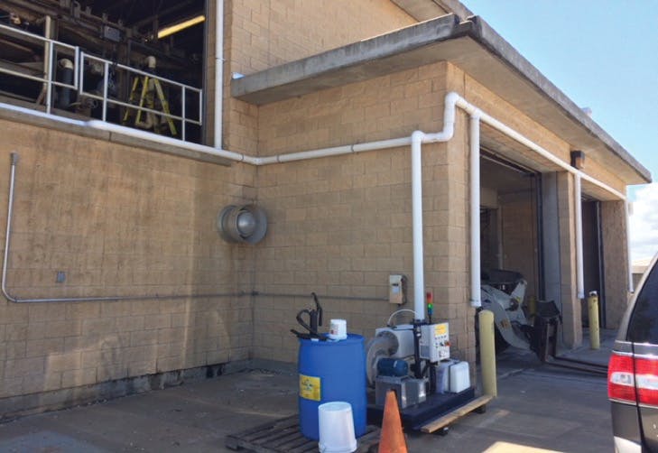 A vapor phase unit treats odors escaping a building. The white ducting is setting up a curtain around the garage/bay doors where odors can escape.