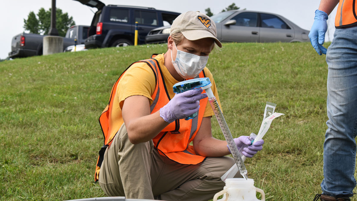 Eric Lundstrom, doctoral student in the Department of Epidemiology, takes a water sample with a pipette.