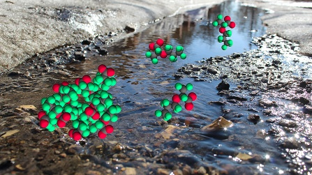 The photo illustration shows GenX molecules, the red and green circles, superimposed over a stream. the interaction between GenX and water lead to the formation of micelles, which occur in higher concentrations near surfaces, like the pebbles of the stream