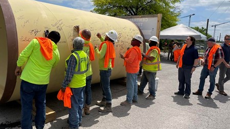 Construction workers sign conveyance piping that will connect two significant portions of the Central Wastewater Treatment Plant improvement project.