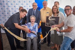 Phyllis Larsen cuts the ribbon in honor of her late husband, Jerry, at the well dedication. Phyllis Larsen cuts the ribbon in honor of her late husband, Jerry, at the well dedication.