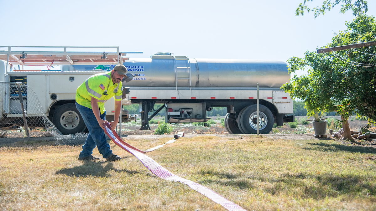 Scott Bambauer of Bambauer Towing delivers water to fill a 1500 gallon potable water tank at a residence in Glenn County, California, where wells have run dry.