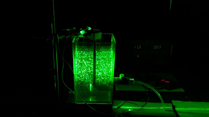 Researchers used a green laser on a jar filled with water to show how the water moves and how contaminants clump together.