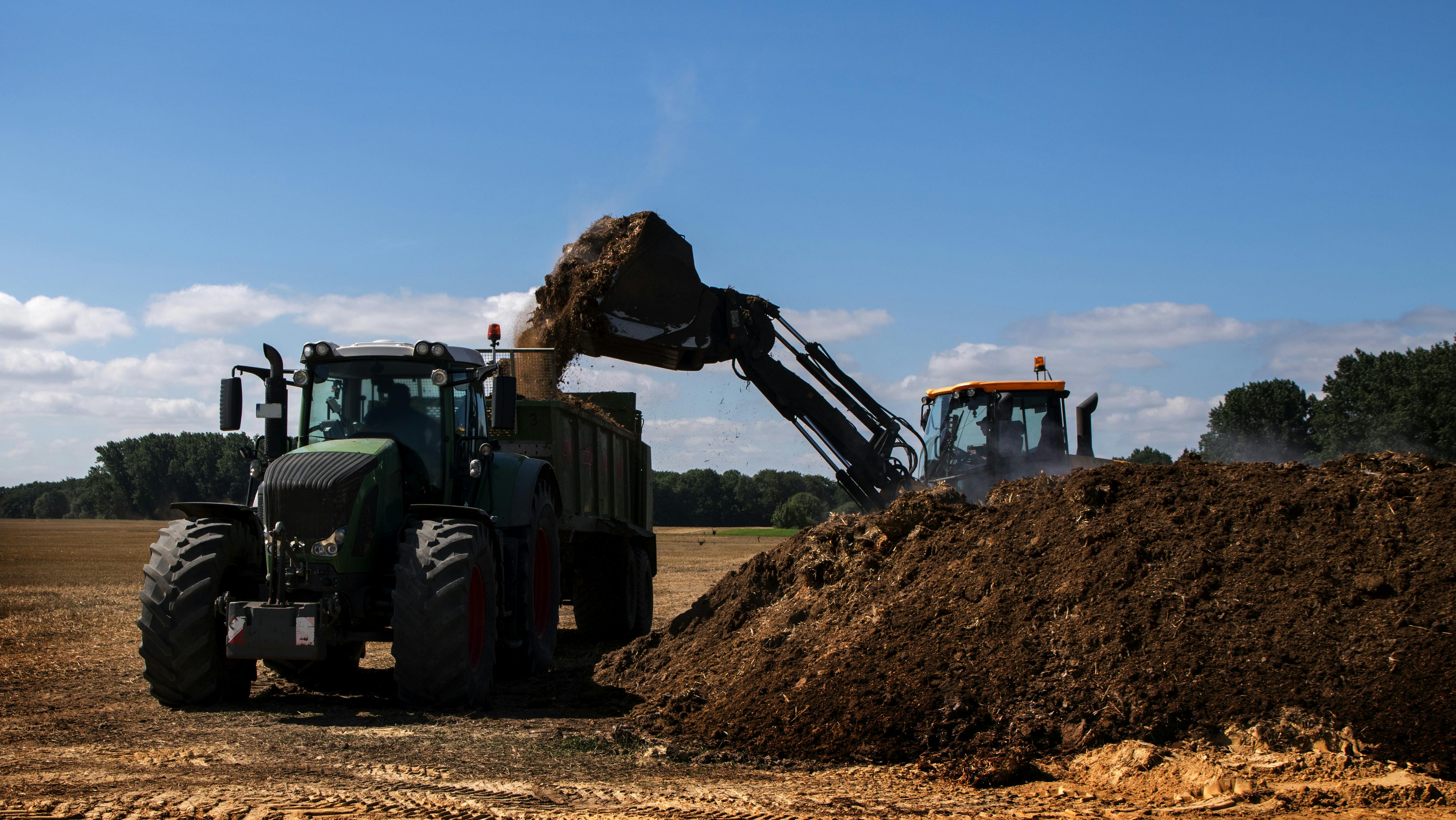 Excavator loads tractor with fertilizer for farming. 57% of wastewater biosolids are land applied as fertilizer in the United States.