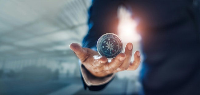 Businessman hand holding compass navigating business direction and successful strategic solution. Reflect accomplishment in terms of research and development growth market and financial profitability.
