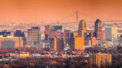 Newark New Jersey skyline viewed from Eagle Rock reservation under an orange sunset. In the background, under a hazy sky, Verrazano bridge links Staten Island to Brooklyn. Newark New Jersey skyline viewed from Eagle Rock reservation under an orange sunset. In the background, under a hazy sky, Verrazano bridge links Staten Island to Brooklyn.