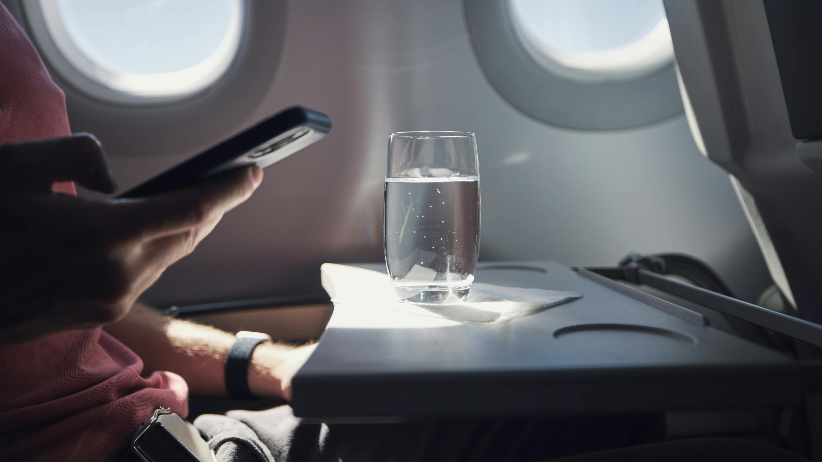 Glass of water on table of seat in airplane