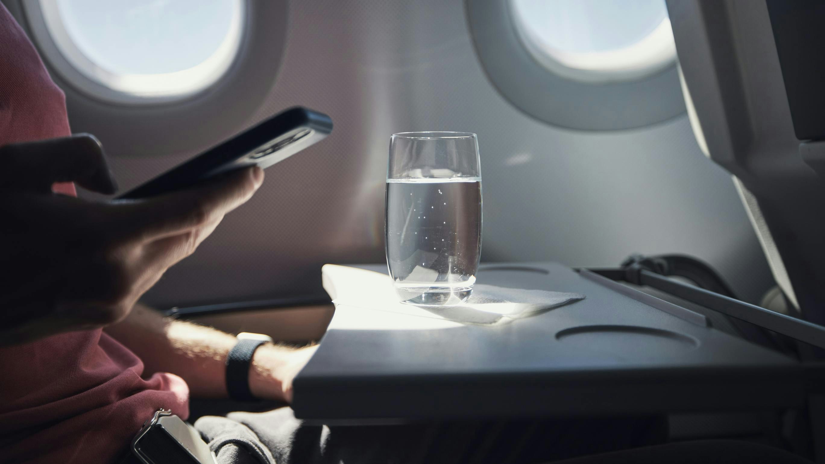 Glass of water on table of seat in airplane