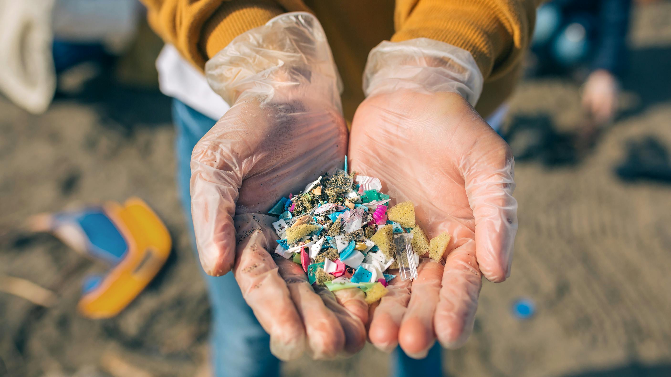 Hands with microplastics on the beach