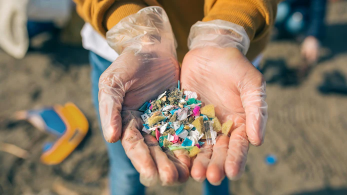 Hands with microplastics on the beach
